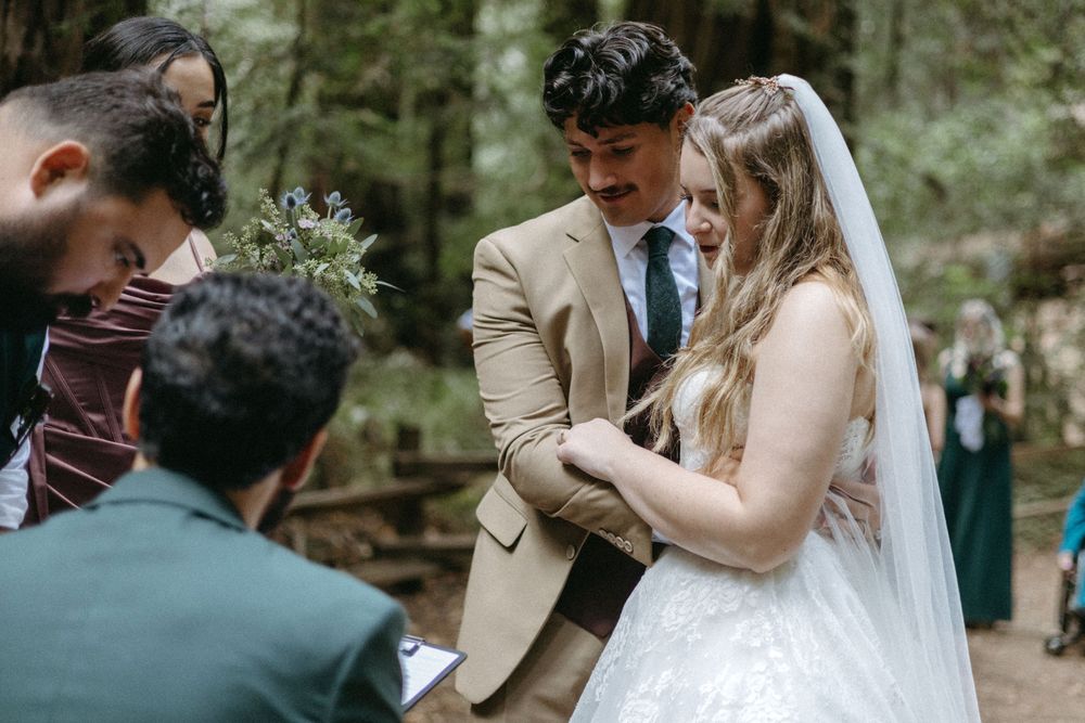A bride and groom standing close in a redwood forest